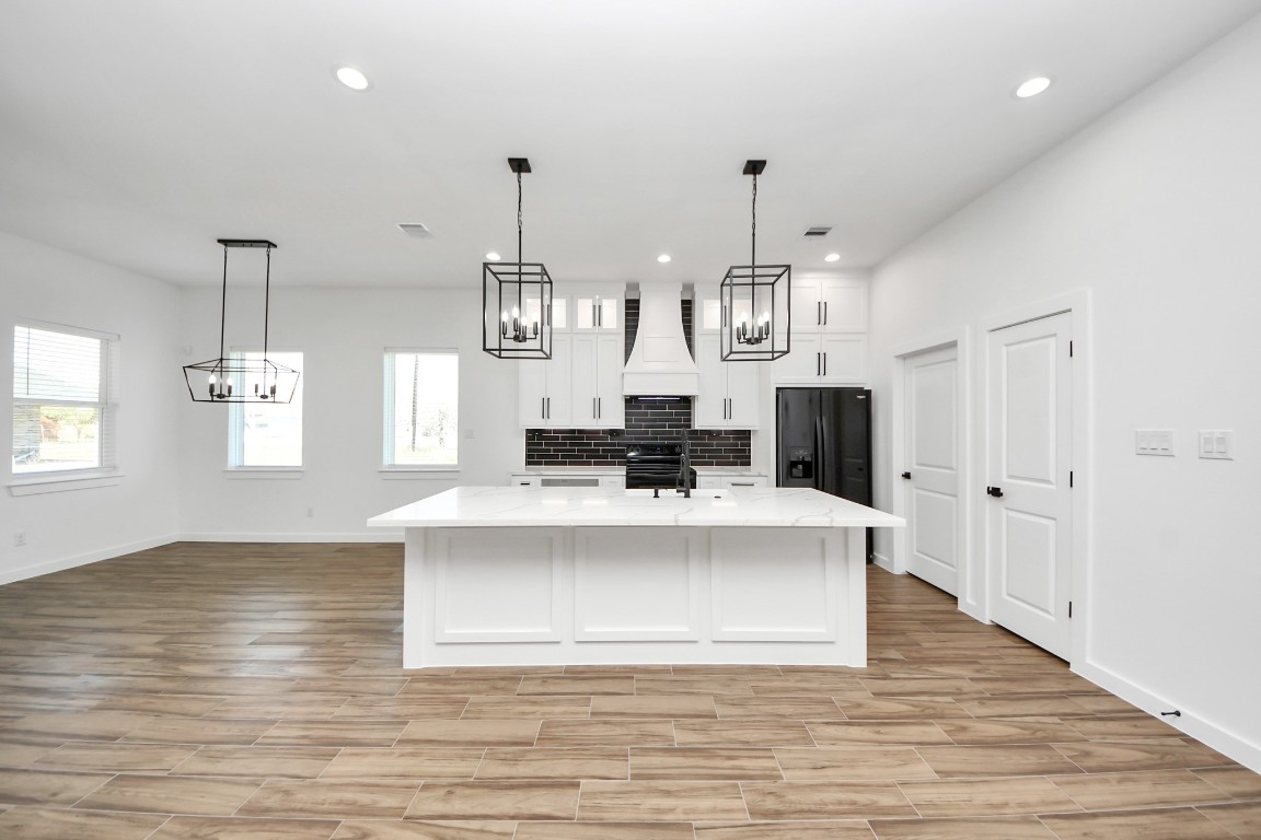207 Manor Avenue Arcola, TX 77583 - Photo 18 of 37 a large white kitchen with a large island oven a stove and a wooden floors