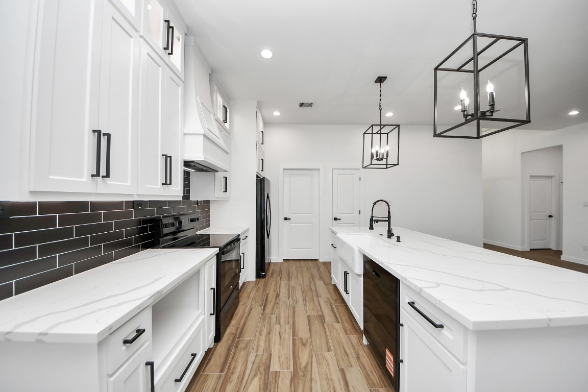 207 Manor Avenue Arcola, TX 77583 - Photo 22 of 37 a kitchen with a sink dishwasher a stove and white cabinets with wooden floor