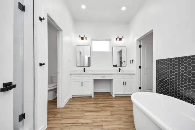 a bathroom with a bathtub a double vanity sink and mirror