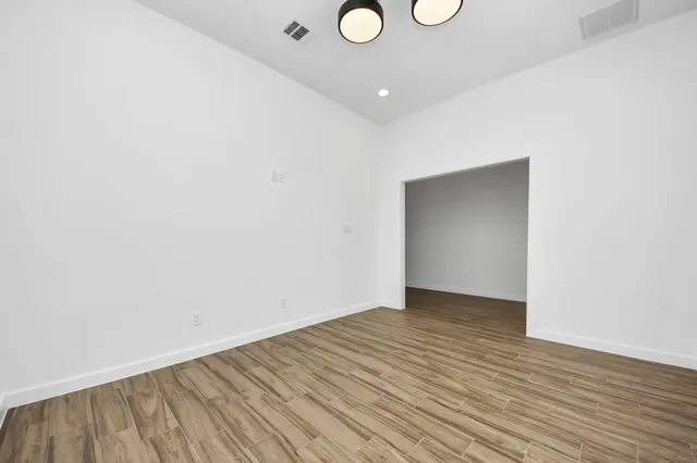 a view of an empty room with wooden floor and a window
