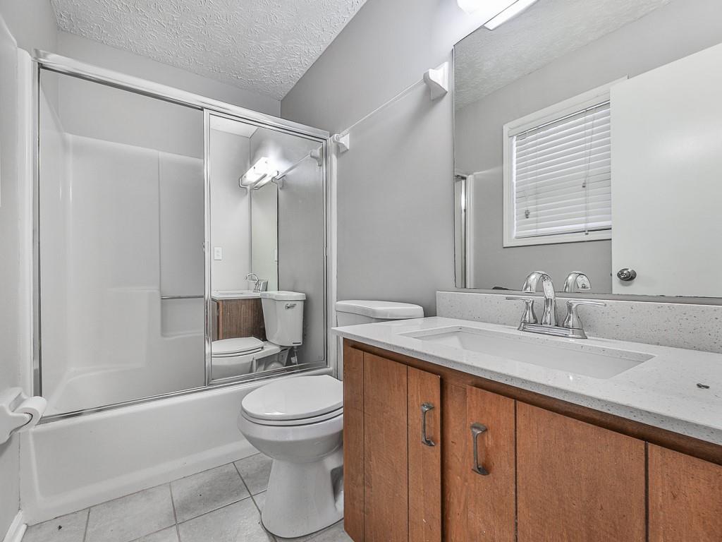 5506 Vaughn Road Woodstock, GA 30188 - Photo 21 of 33 a bathroom with a granite countertop sink toilet a mirror and shower