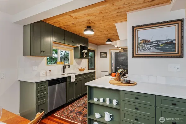 a living room with stainless steel appliances kitchen island granite countertop furniture and a wooden floor