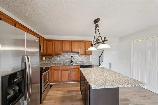a kitchen with kitchen island granite countertop a sink a counter top space appliances and cabinets