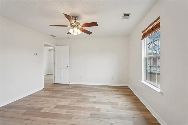 a view of empty room with wooden floor and fan