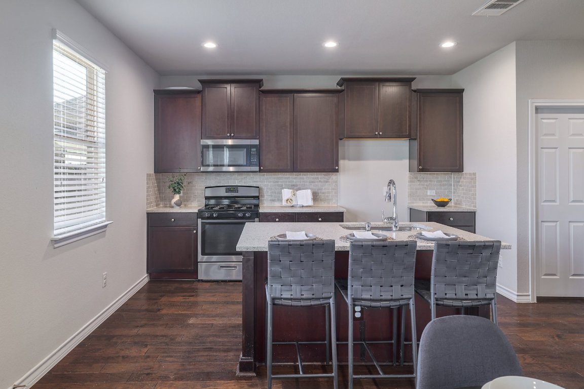 6792 Catania Loop Round Rock, TX 78665 - Photo 7 of 31 a kitchen with kitchen island granite countertop wooden cabinets and a refrigerator