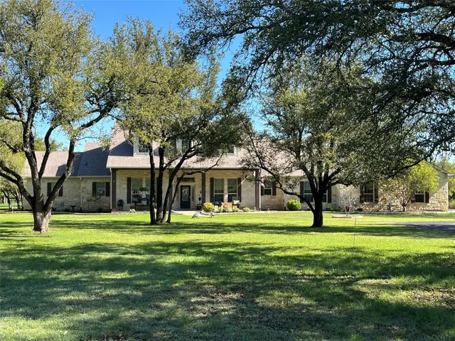 a front view of a house with a big yard and trees