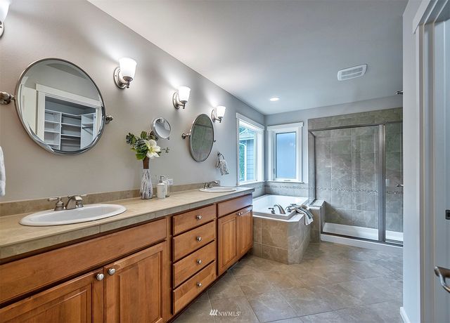 a spacious bathroom with a double vanity sink mirror and bathtub