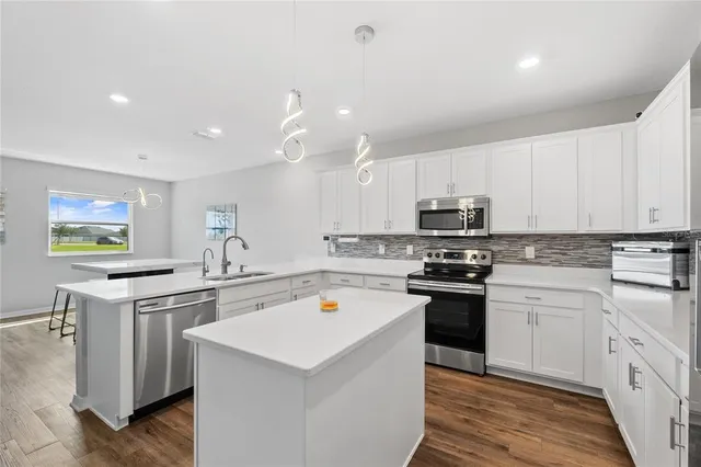 a kitchen with a sink a stove a refrigerator and white cabinets
