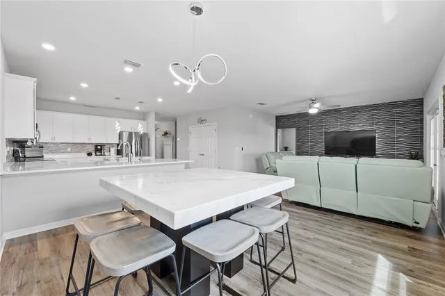 a kitchen with stainless steel appliances kitchen island granite countertop a table chairs sink and cabinets