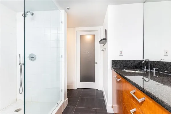 a bathroom with a granite countertop sink a mirror and shower
