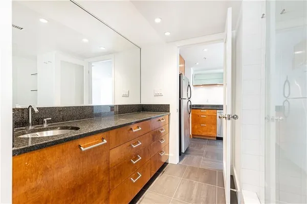 a spacious bathroom with a granite countertop sink mirror and a bathtub