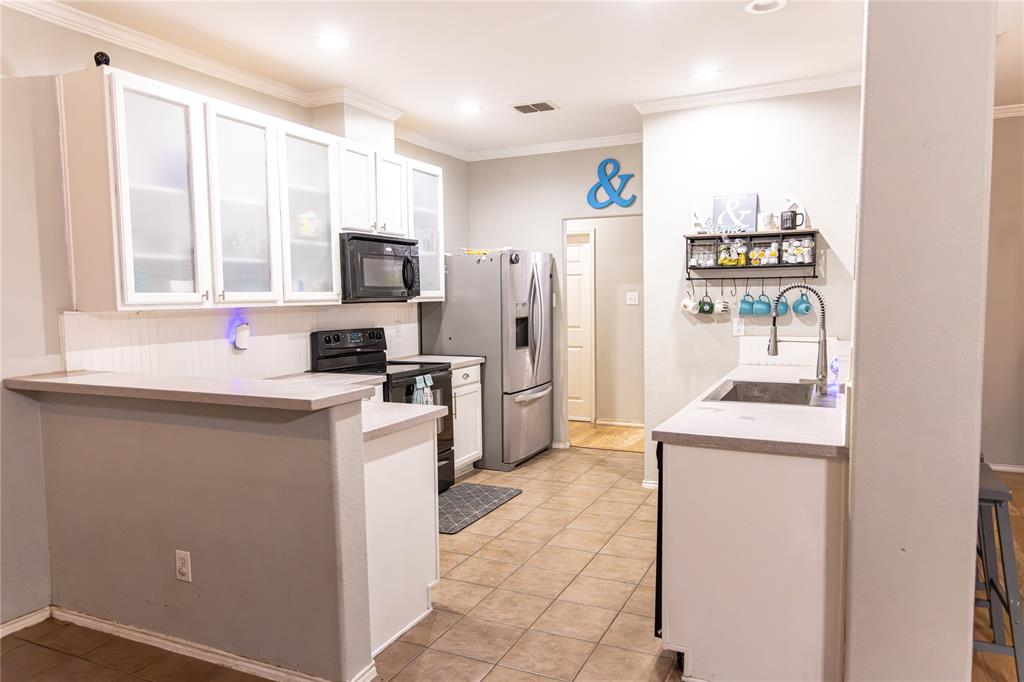 104 South Forest Grove Princeton, TX 75407 - Photo 9 of 36 a kitchen with stainless steel appliances a refrigerator and a stove top oven