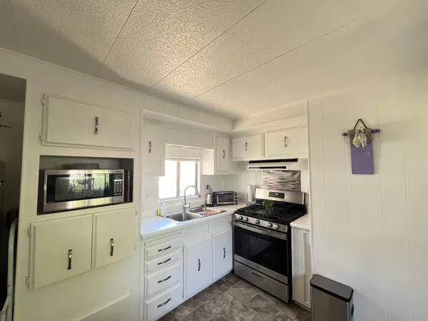 a kitchen with granite countertop white cabinets and stainless steel appliances