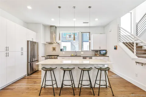 a kitchen with stainless steel appliances granite countertop a stove a refrigerator a sink a dining table and chairs with wooden floor