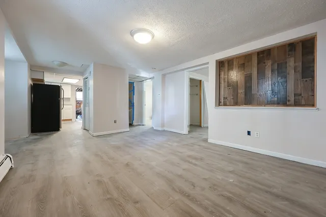 a view of an empty room with wooden floor and windows
