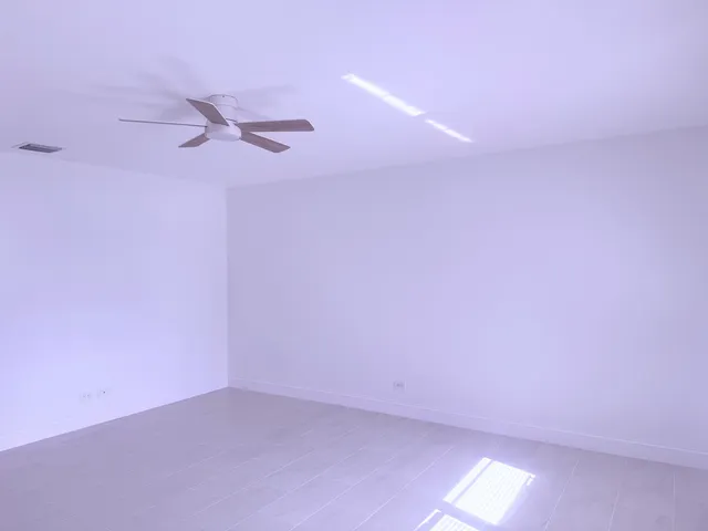 an empty room with windows and fan