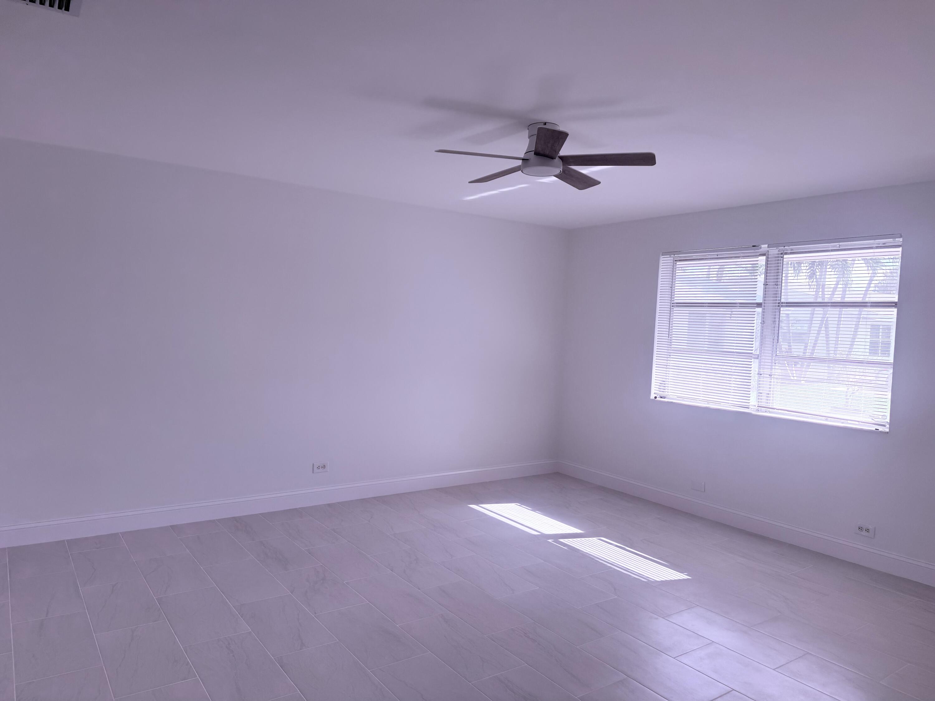 630 Prosperity Farms Road, Unit 1 North Palm Beach, FL 33408 - Photo 12 of 16 an empty room with windows and fan