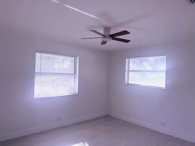 an empty room with a ceiling fan and a window