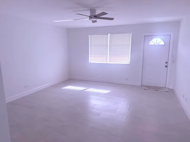 an empty room with windows and fan