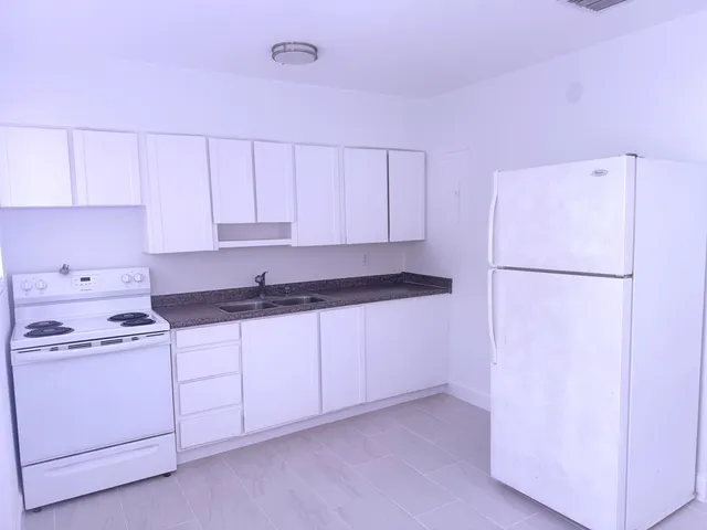 a kitchen with a refrigerator sink and cabinets