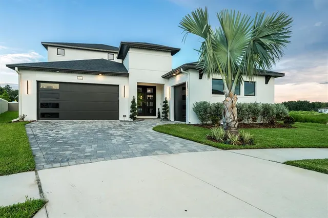 a front view of a house with a garden and palm trees