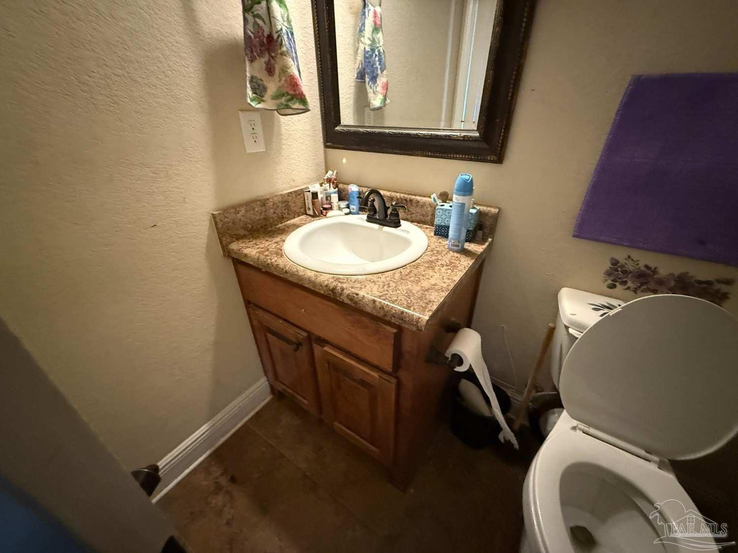8826 Bluebell Street Milton, FL 32583 - Photo 17 of 25 a bathroom with a granite countertop toilet a sink and a mirror