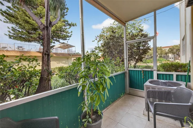 a balcony with couple of chairs and a potted plant