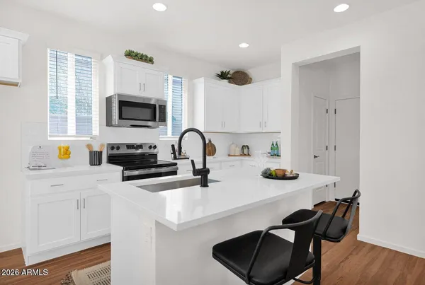 a kitchen with stainless steel appliances a sink a stove a microwave a refrigerator and cabinets