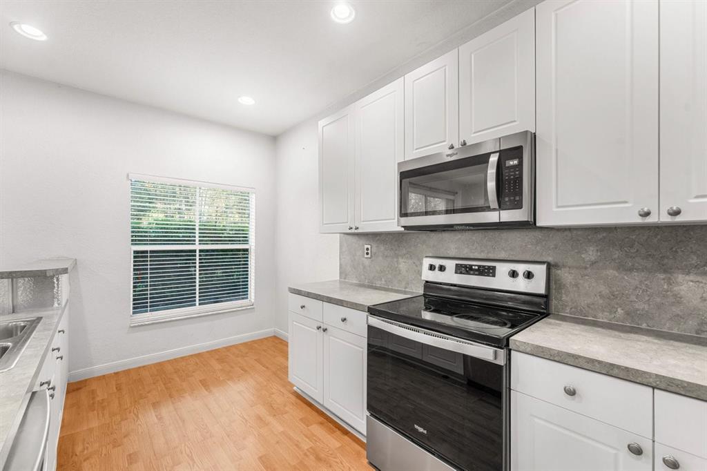 3307 Merrick Lane, Unit 1004 Margate, FL 33063 - Photo 5 of 30 a kitchen with stainless steel appliances a stove a microwave sink and cabinets