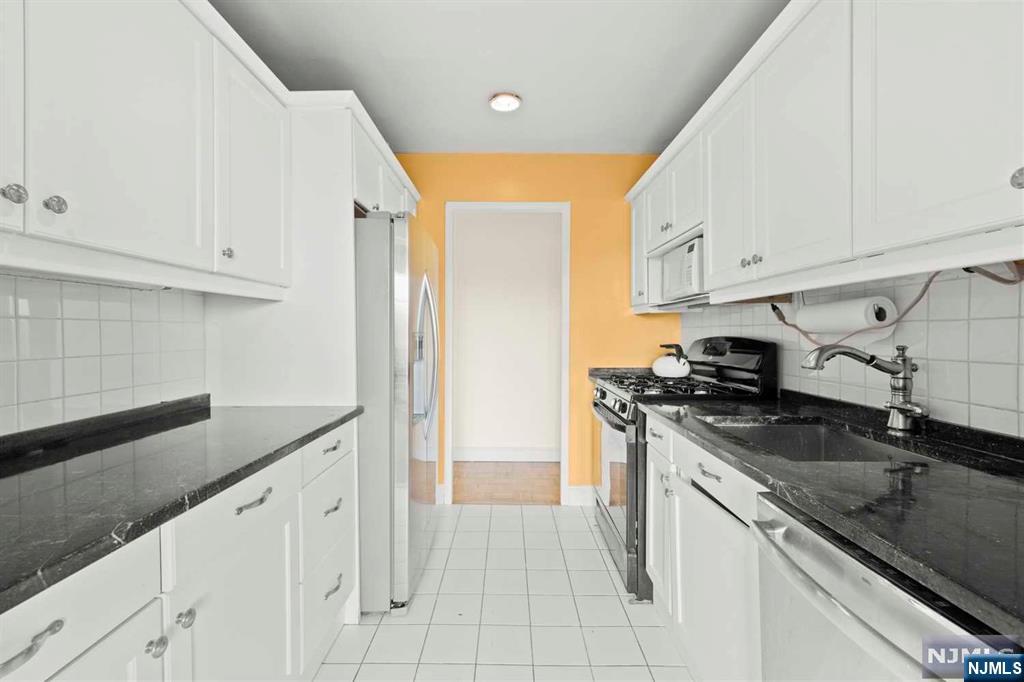 1375 River Road, Unit 4D Edgewater, NJ 07020 - Photo 16 of 25 a kitchen with granite countertop a sink stainless steel appliances and white cabinets