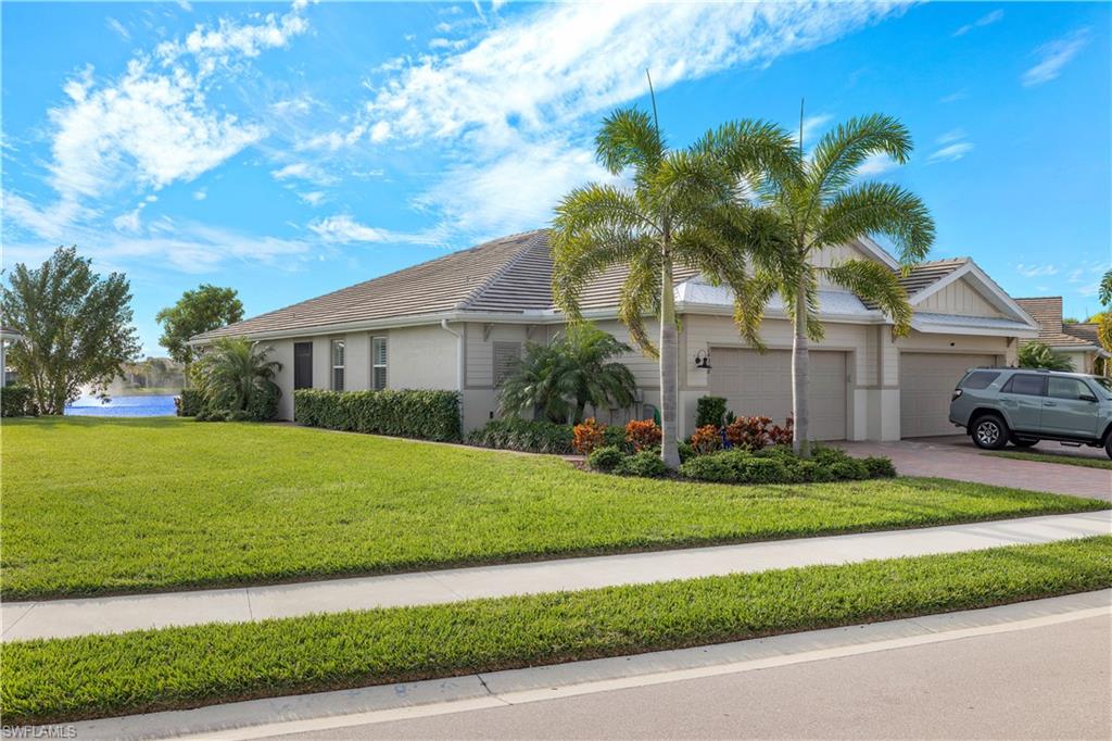 14558 Edgewater Circle Naples, FL 34114 - Photo 23 of 40 a front view of a house with a garden and trees