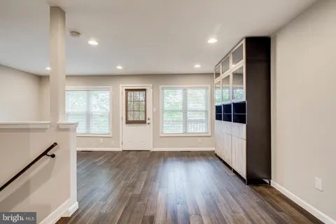 a view of an empty room with wooden floor and windows