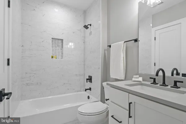 a bathroom with a granite countertop sink a toilet and a bathtub