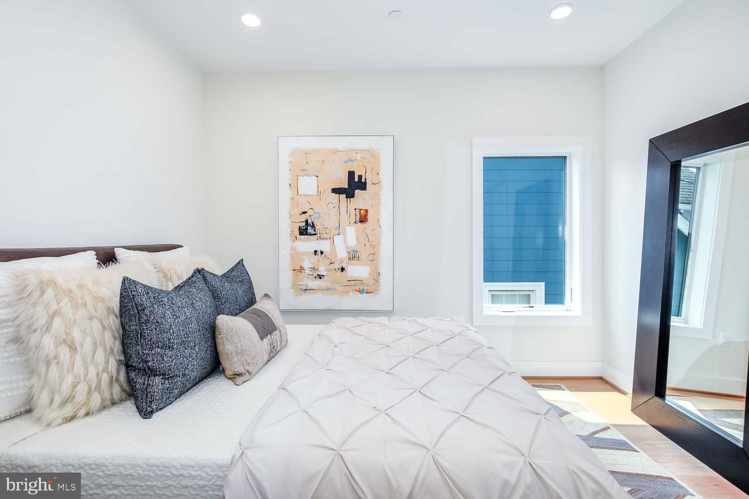 1818 Rhode Island Avenue Northeast, Unit 4 Washington, DC 20018 - Photo 10 of 15 a large bed sitting in a bedroom next to a window and a lamp