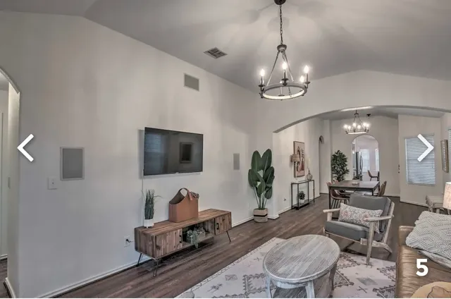 a living room with furniture a chandelier and a flat screen tv