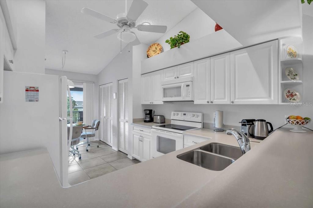 6807 Stone River Road, Unit 204 Bradenton, FL 34203 - Photo 7 of 54 a kitchen with stainless steel appliances granite countertop a sink dishwasher a refrigerator and white cabinets with wooden floor