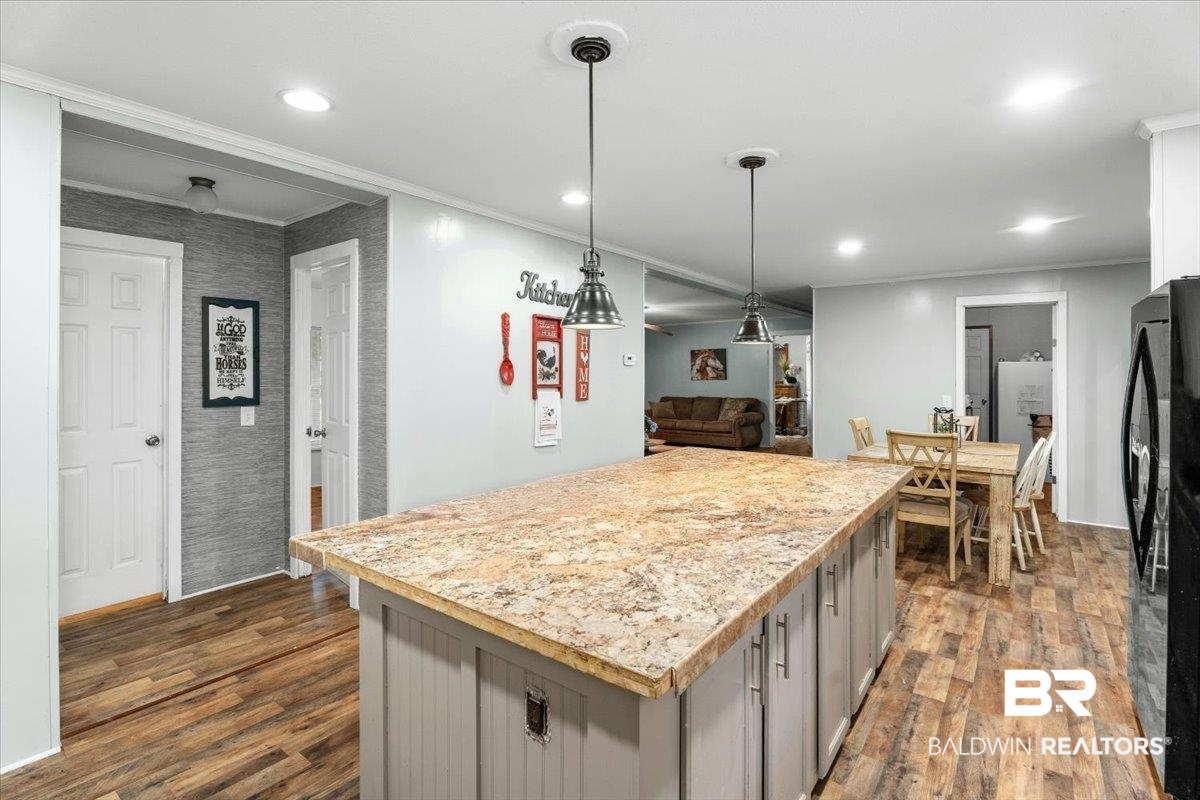 21011 River Road Robertsdale, AL 36567 - Photo 7 of 29 Kitchen island featuring a stone-finish countertop with pendant lighting, wood-finish flooring, recessed ceiling lights, and white trim