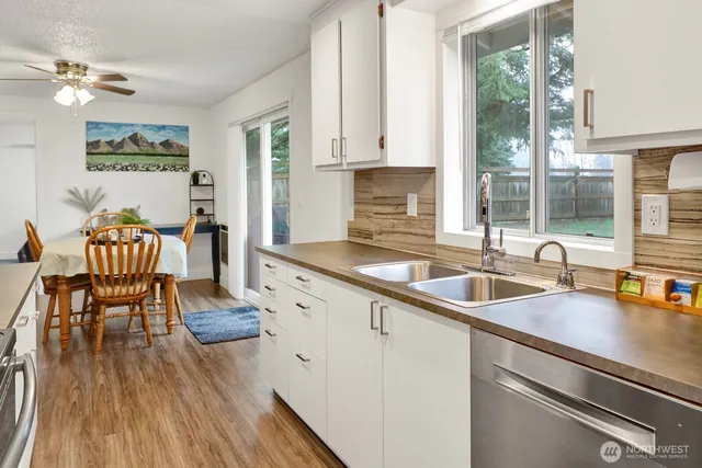 a kitchen with stainless steel appliances granite countertop a sink dishwasher a stove and a dining table with wooden cabinet