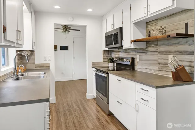 a kitchen with stainless steel appliances granite countertop a sink a stove a refrigerator and cabinets