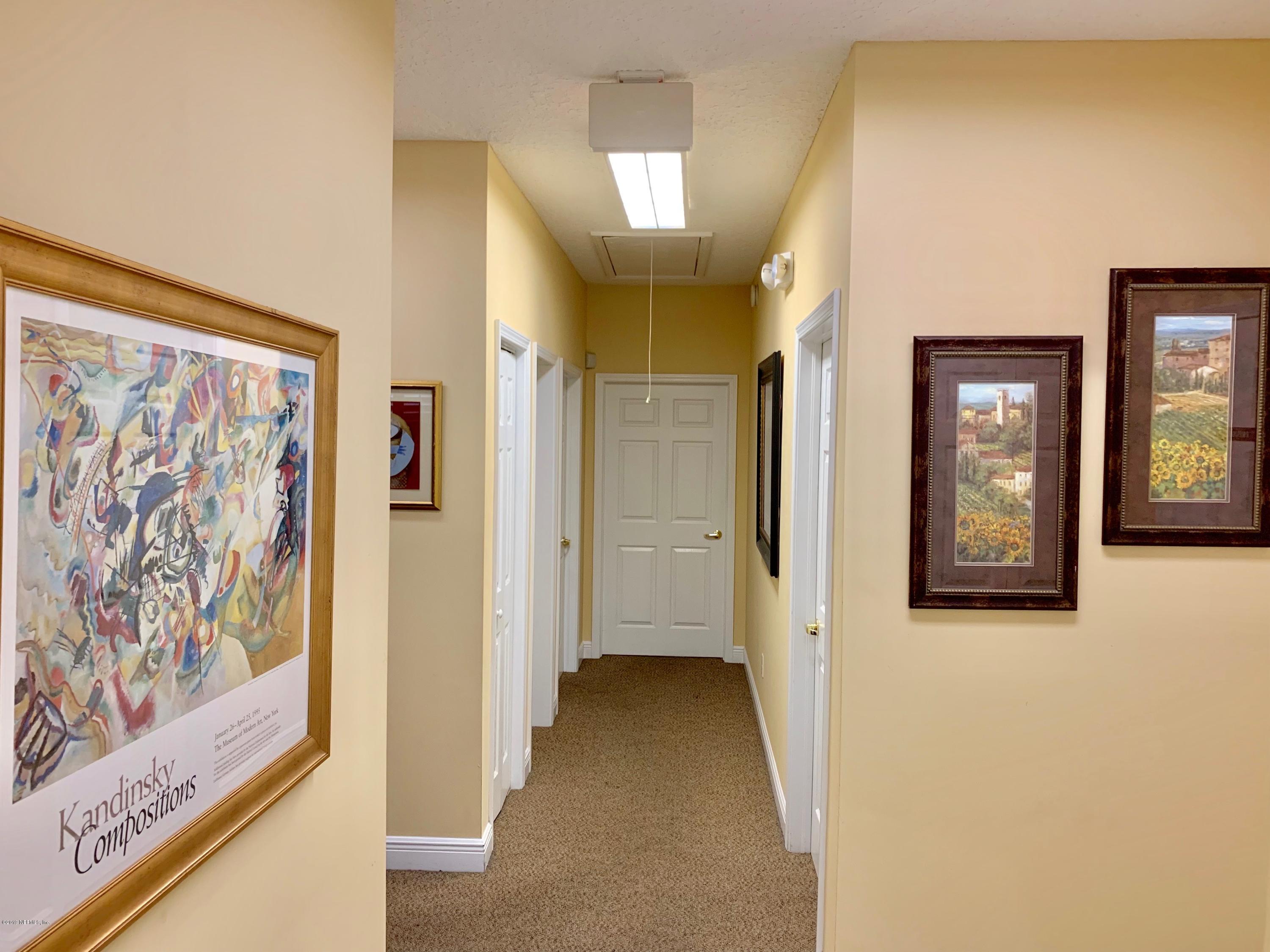 a view of a hallway with wooden floor and windows