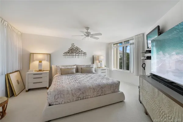 a bedroom with a bed and a flat tv screen on dresser