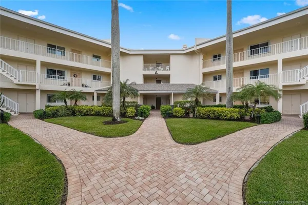 a view of a white building with a yard and plants