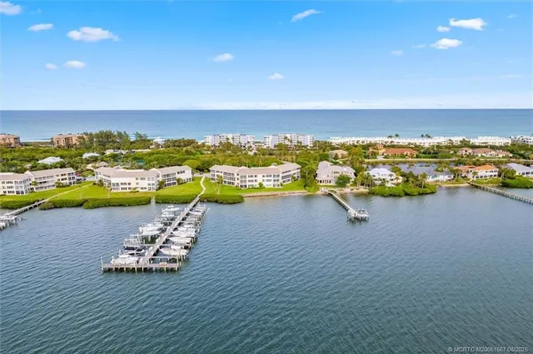 an aerial view of ocean and residential houses with outdoor space
