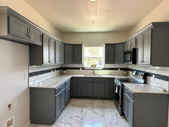 a large kitchen with a sink and dishwasher a stove top oven with wooden floor