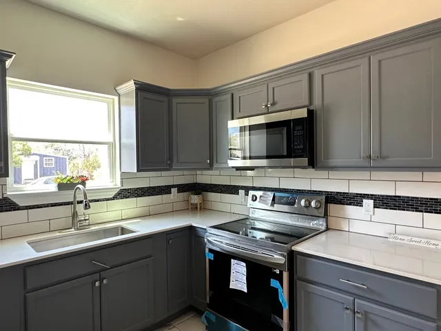 a kitchen with stainless steel appliances granite countertop a sink stove and microwave