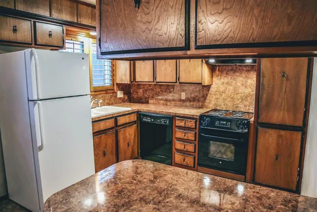 a kitchen with stainless steel appliances granite countertop a refrigerator a stove a sink and dishwasher