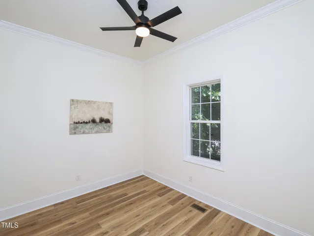 a view of an empty room with wooden floor and a bathroom