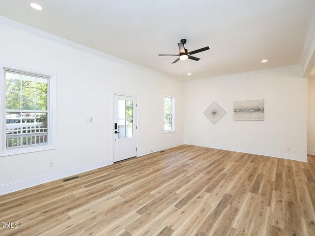 a view of empty room with wooden floor and fan