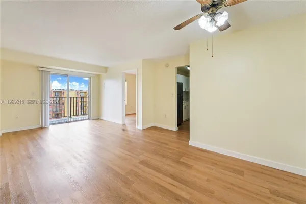 a view of an empty room with a window and wooden floor