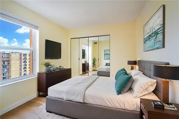 a bedroom with a bed television on desk and a window